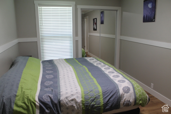 Bedroom with wood finished floors and a closet
