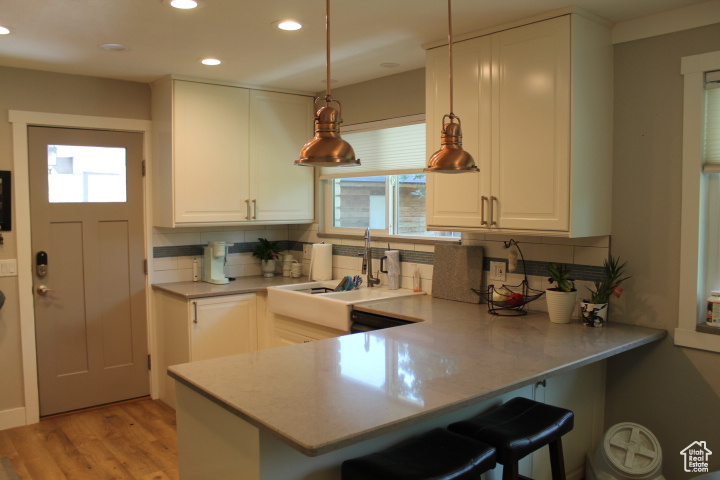 Kitchen featuring decorative backsplash, recessed lighting, a peninsula, a kitchen breakfast bar, and white cabinets