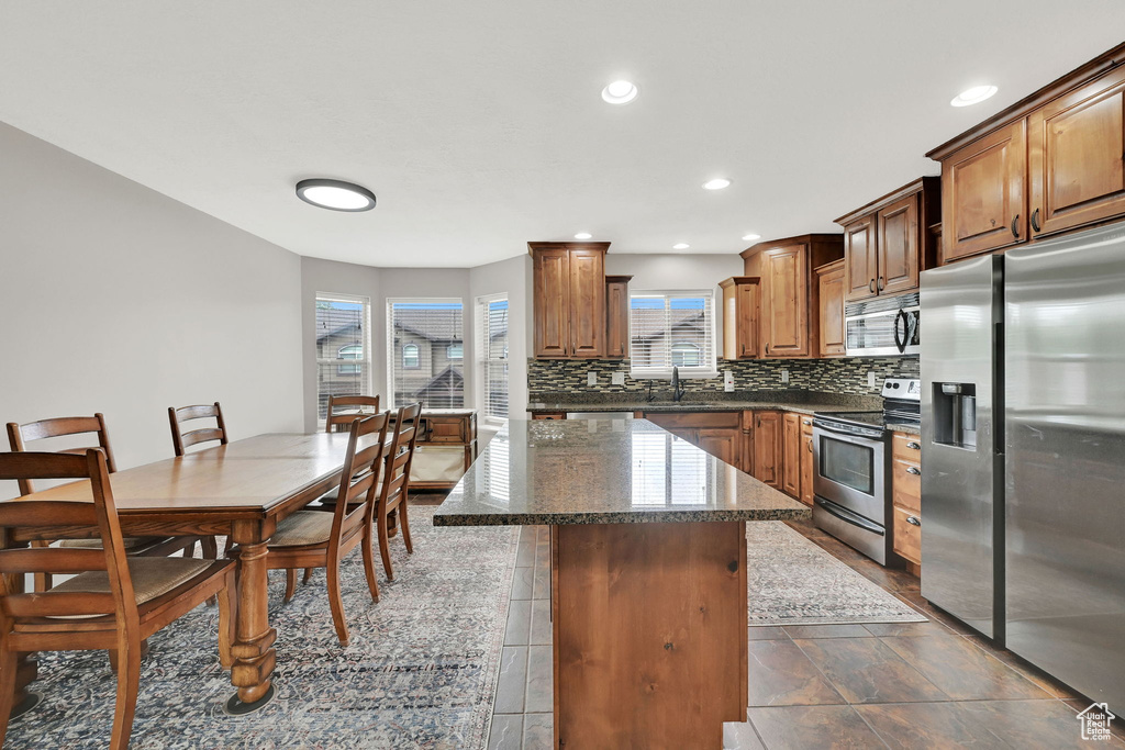 Kitchen featuring stainless steel appliances, decorative backsplash, a center island, dark stone counters, and recessed lighting
