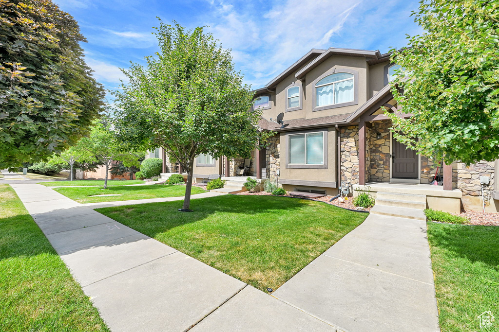 View of front of house with stone siding, stucco siding, and a front lawn