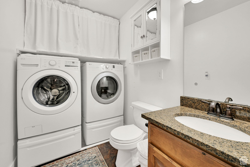 Bathroom featuring washer and dryer, vanity, and wood finished floors