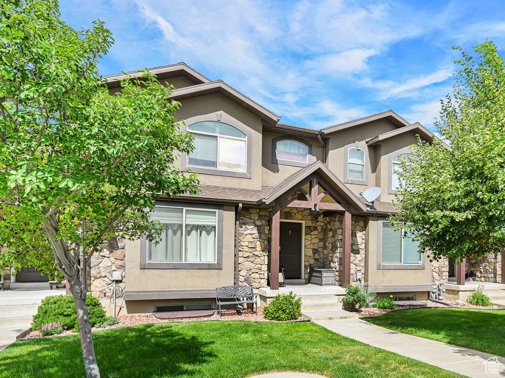 View of front of home featuring stone siding, stucco siding, and a front yard