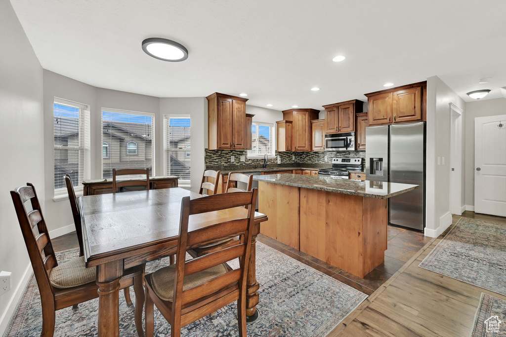 Kitchen with stainless steel appliances, a kitchen island, tasteful backsplash, recessed lighting, and dark stone counters