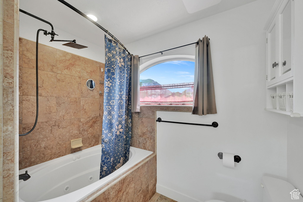Full bath with a combined bath / shower with jetted tub and toilet