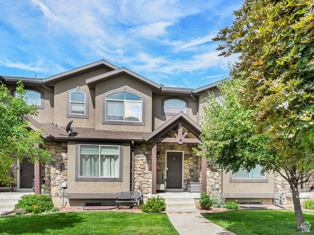 View of front of property with stucco siding, stone siding, and a front yard