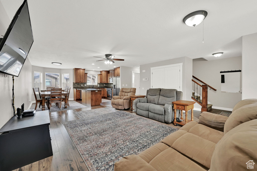 Living room with a ceiling fan, light wood finished floors, stairway, and recessed lighting