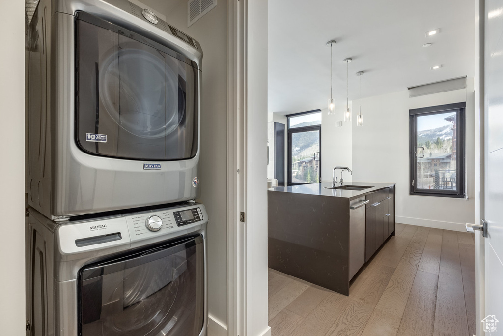 Laundry area featuring stacked washer / dryer and light wood-style floors