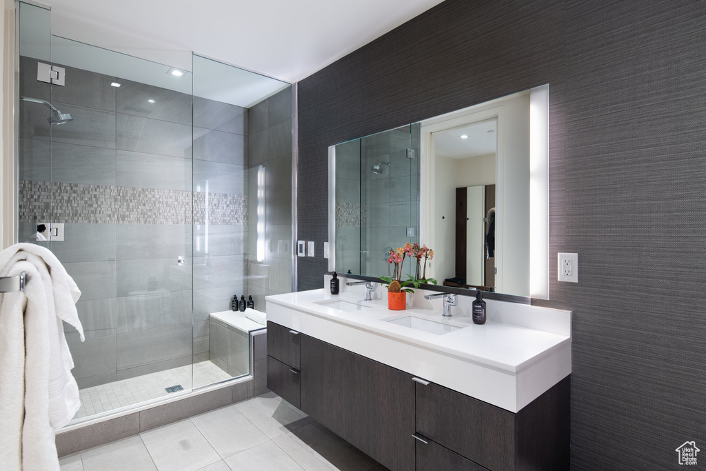 Bathroom featuring tile patterned floors, double vanity, a stall shower, and tile walls