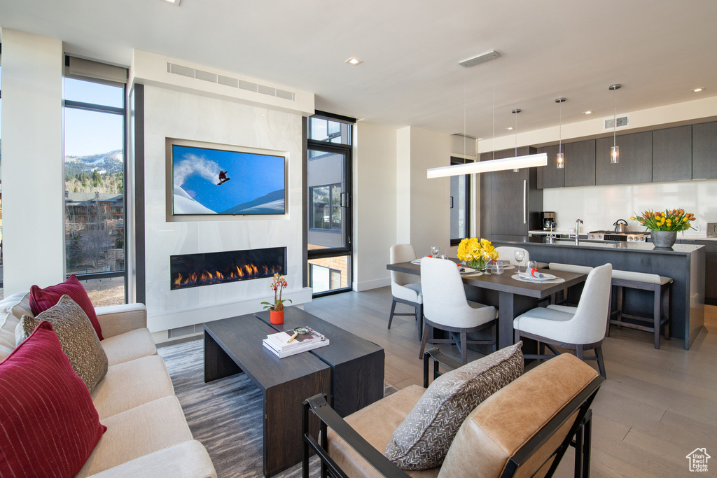Living area featuring wood finished floors, plenty of natural light, a glass covered fireplace, recessed lighting, and floor to ceiling windows