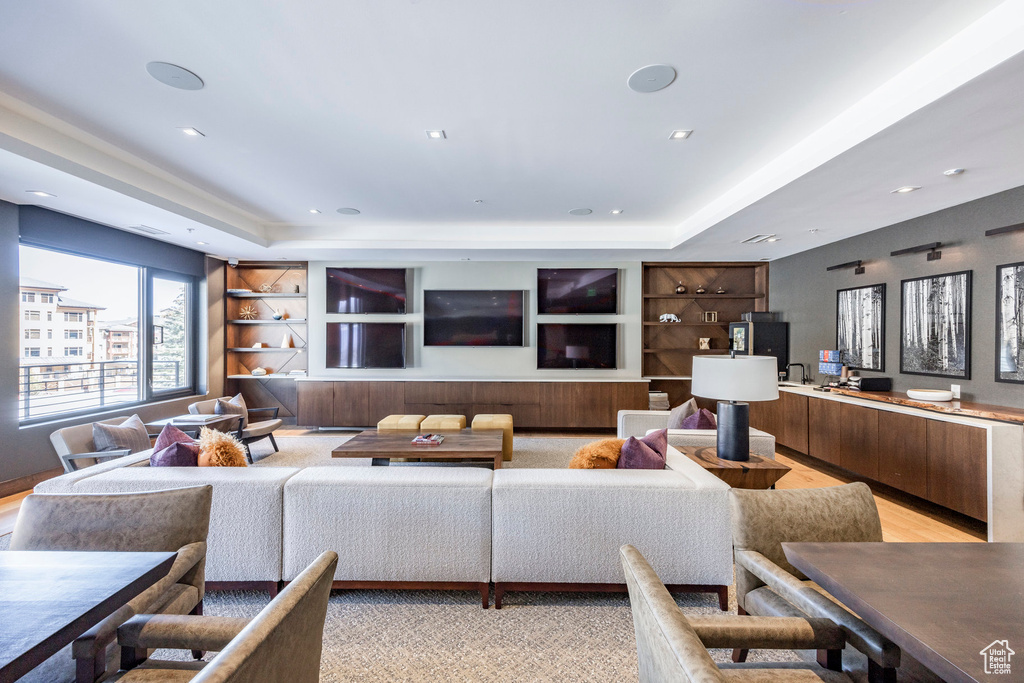 Living room with a tray ceiling and light wood-style floors