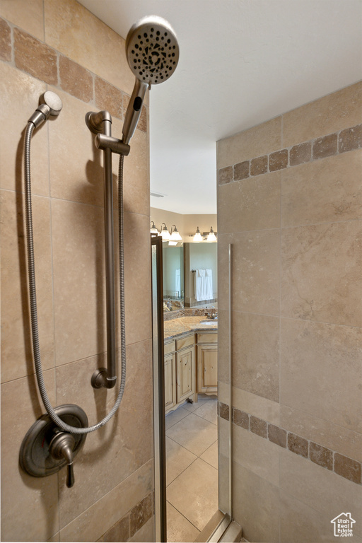 Full bath featuring a tile shower, vanity, and tile patterned floors