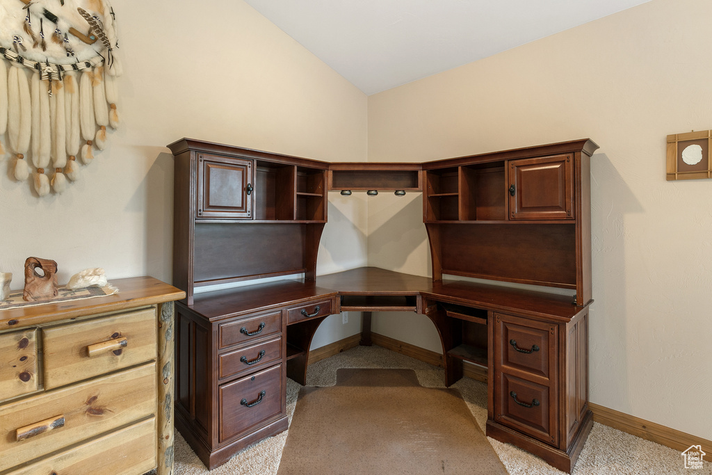 Home office featuring light carpet, vaulted ceiling, and built in study area