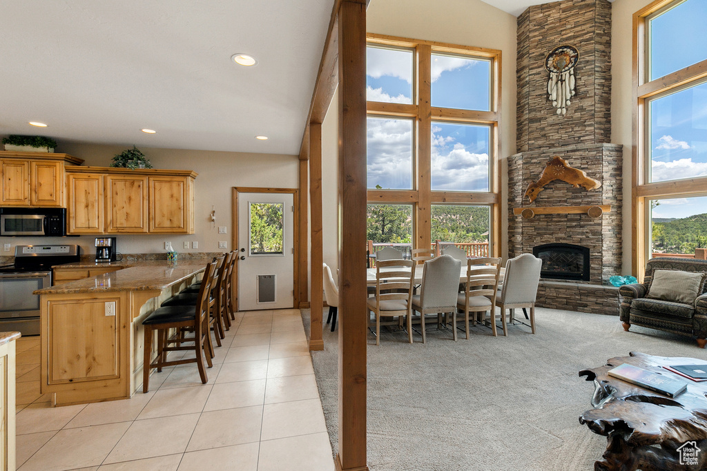 Kitchen featuring stainless steel appliances, light tile patterned floors, a breakfast bar area, recessed lighting, and a peninsula