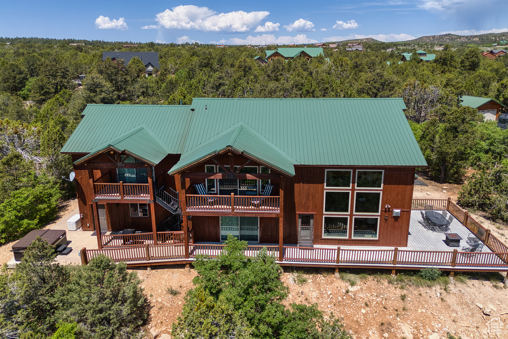 Back of house with a deck, a metal roof, and a balcony