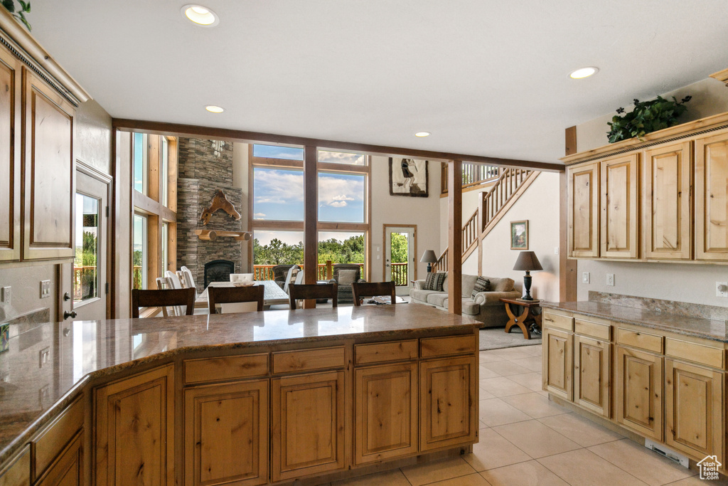 Kitchen featuring a fireplace, recessed lighting, stone countertops, light tile patterned floors, and open floor plan