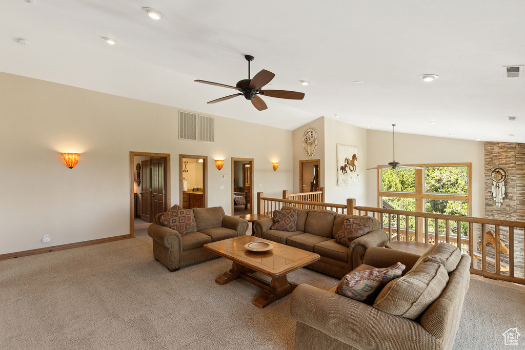 Living area with ceiling fan, light colored carpet, and high vaulted ceiling