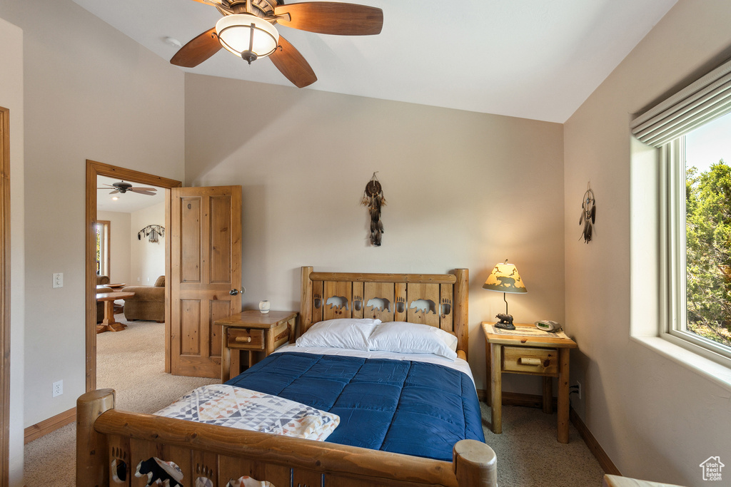 Carpeted bedroom featuring multiple windows, a ceiling fan, and vaulted ceiling