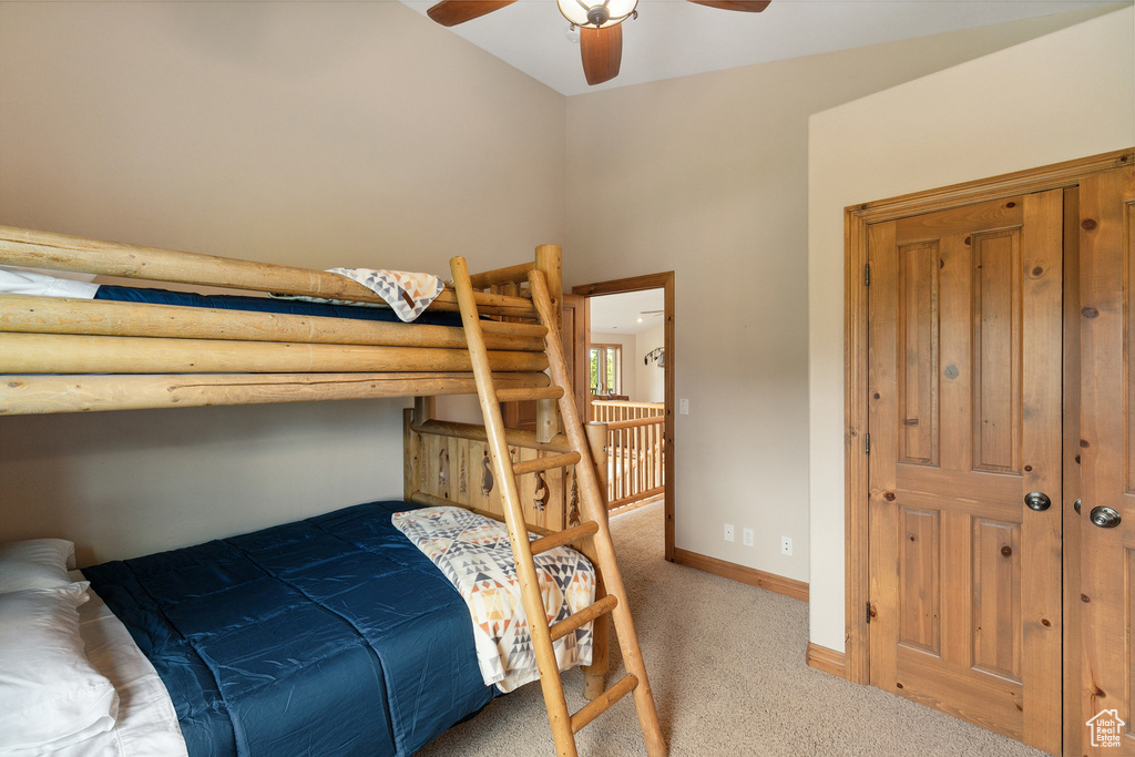 Carpeted bedroom featuring vaulted ceiling and a ceiling fan