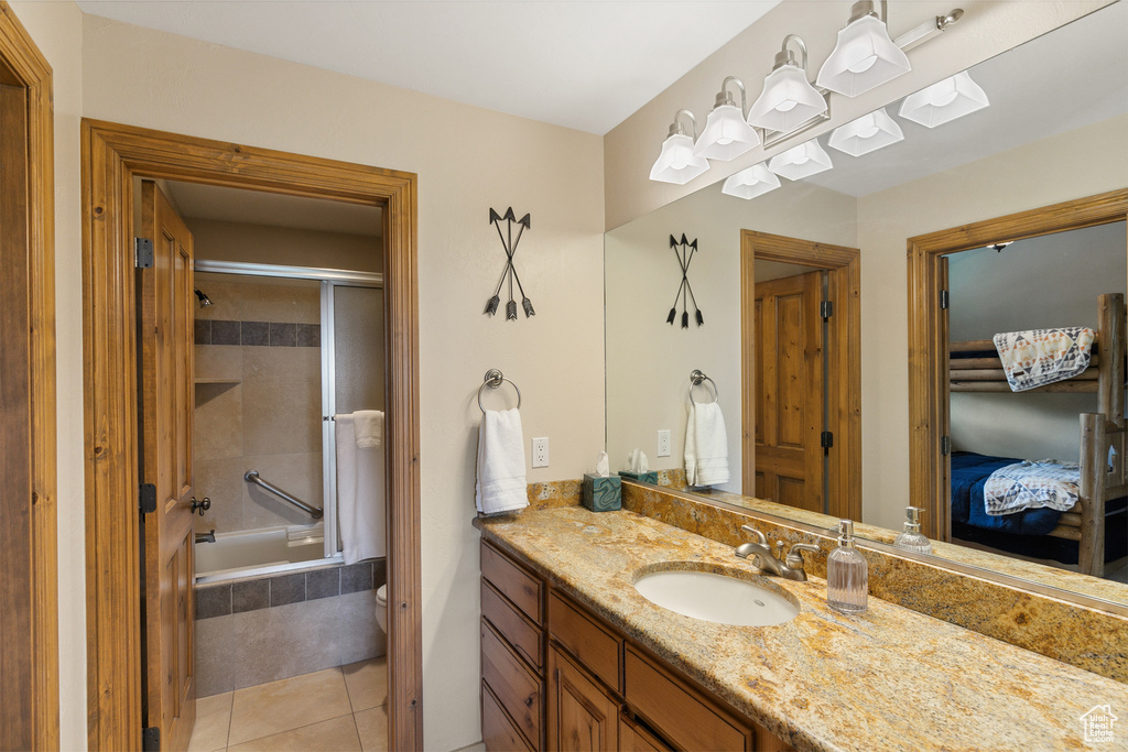 Bathroom with vanity, connected bathroom, tile patterned floors, and tiled shower / bath combo