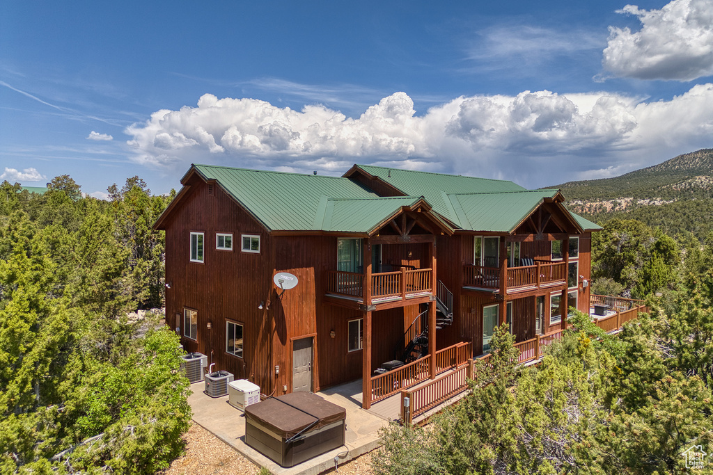 Back of property with a patio area, a deck, stairway, and a metal roof