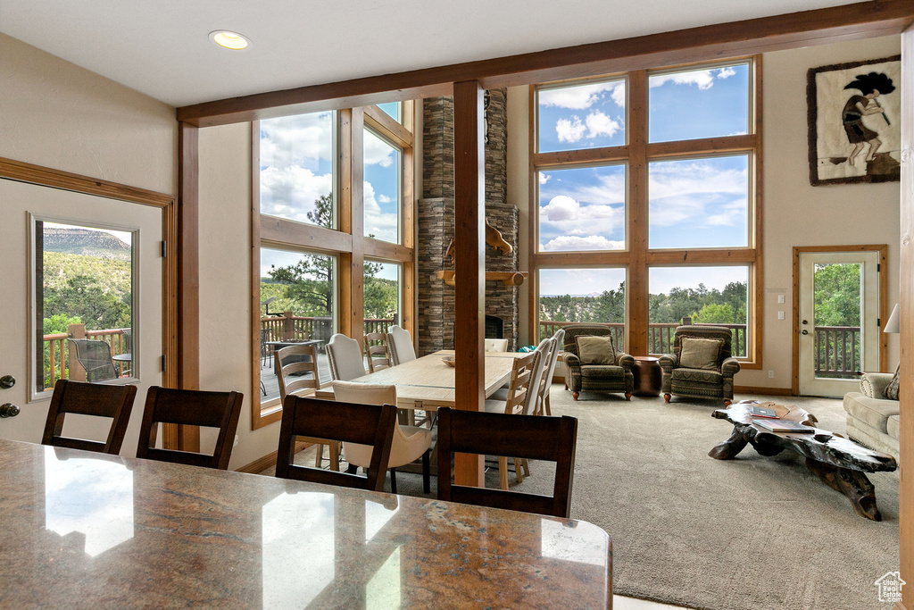 Carpeted dining room featuring a towering ceiling, plenty of natural light, and recessed lighting