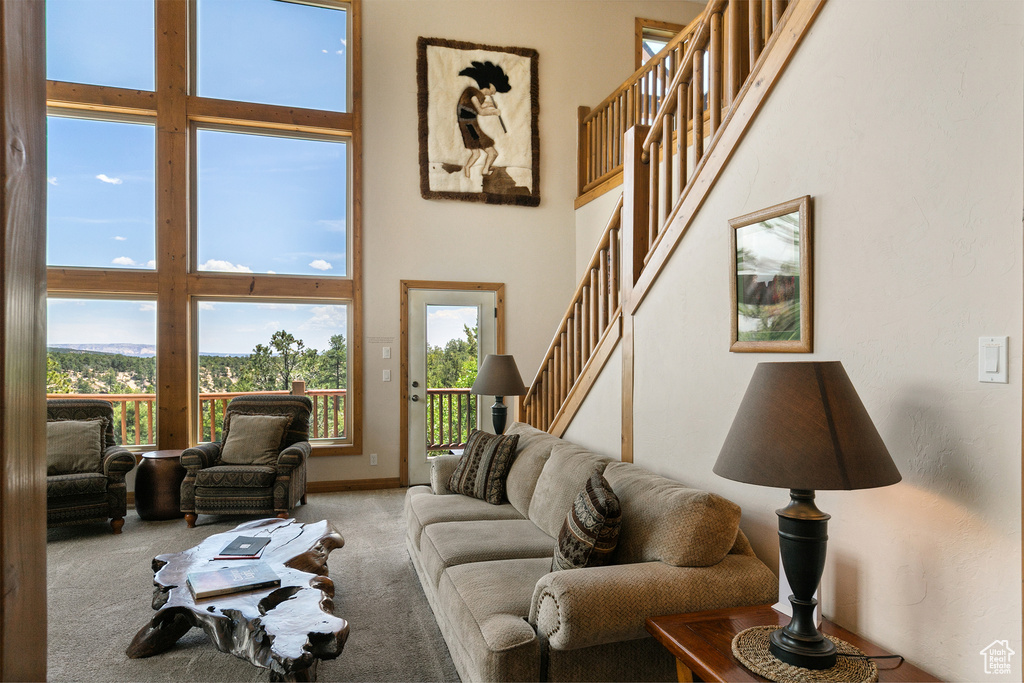 Carpeted living area featuring a towering ceiling and stairs