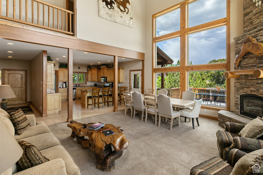 Living area with a high ceiling, recessed lighting, a stone fireplace, and light tile patterned flooring