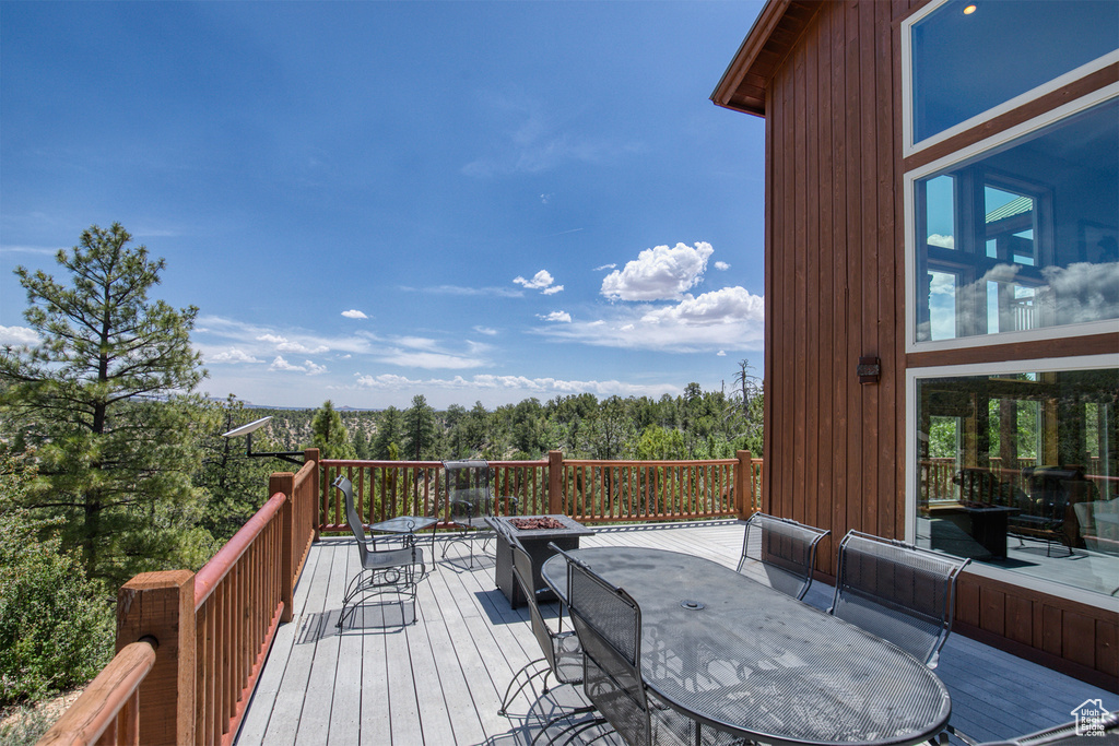Wooden deck with outdoor dining area and a wooded view