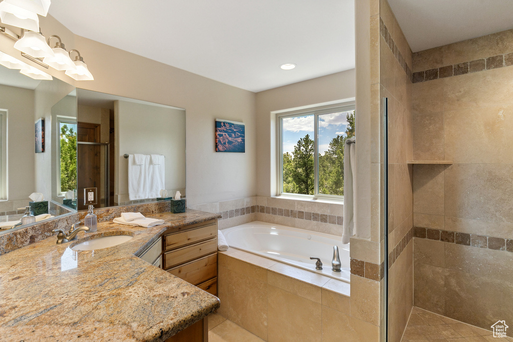 Full bath featuring vanity, a garden tub, and a stall shower