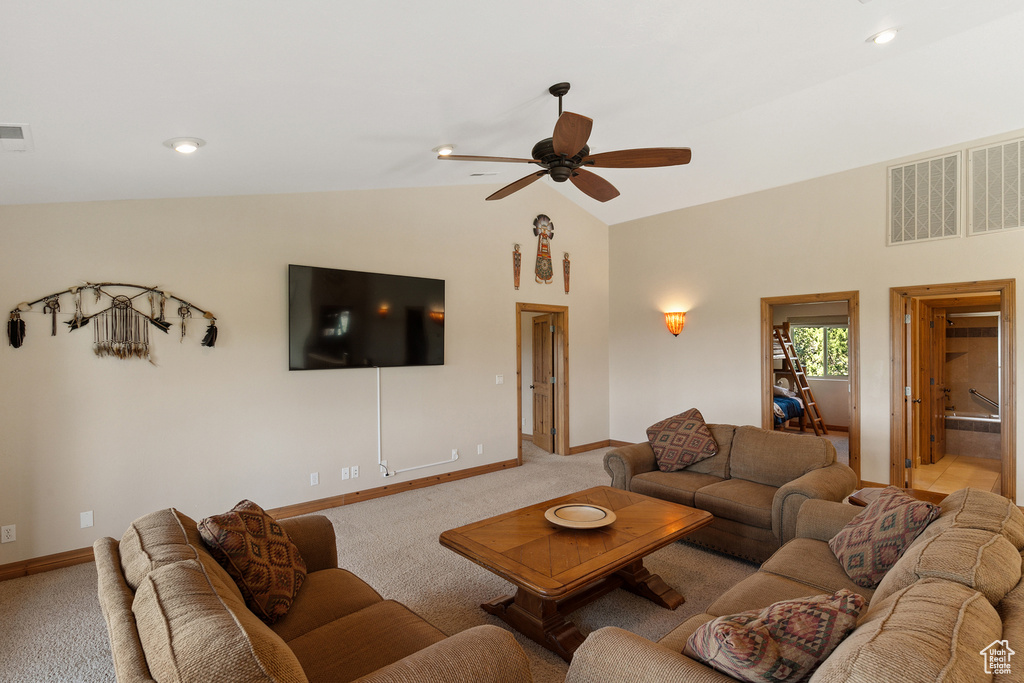 Living room with carpet floors, ceiling fan, and high vaulted ceiling