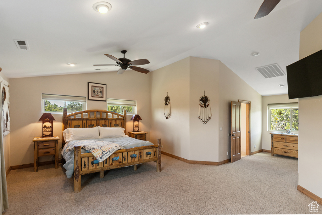 Bedroom with vaulted ceiling, light colored carpet, and ceiling fan