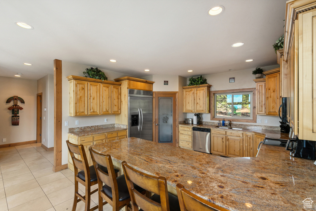 Kitchen featuring stainless steel appliances, a peninsula, recessed lighting, light tile patterned floors, and a breakfast bar area