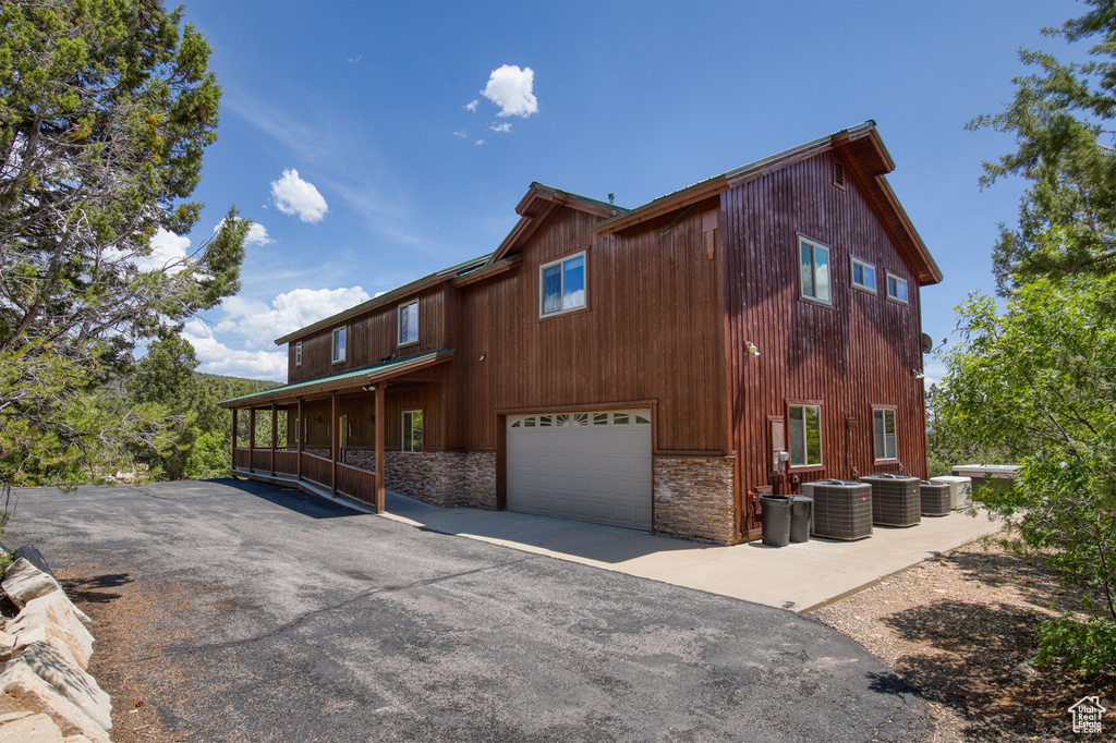 Rear view of house featuring stone siding and a garage