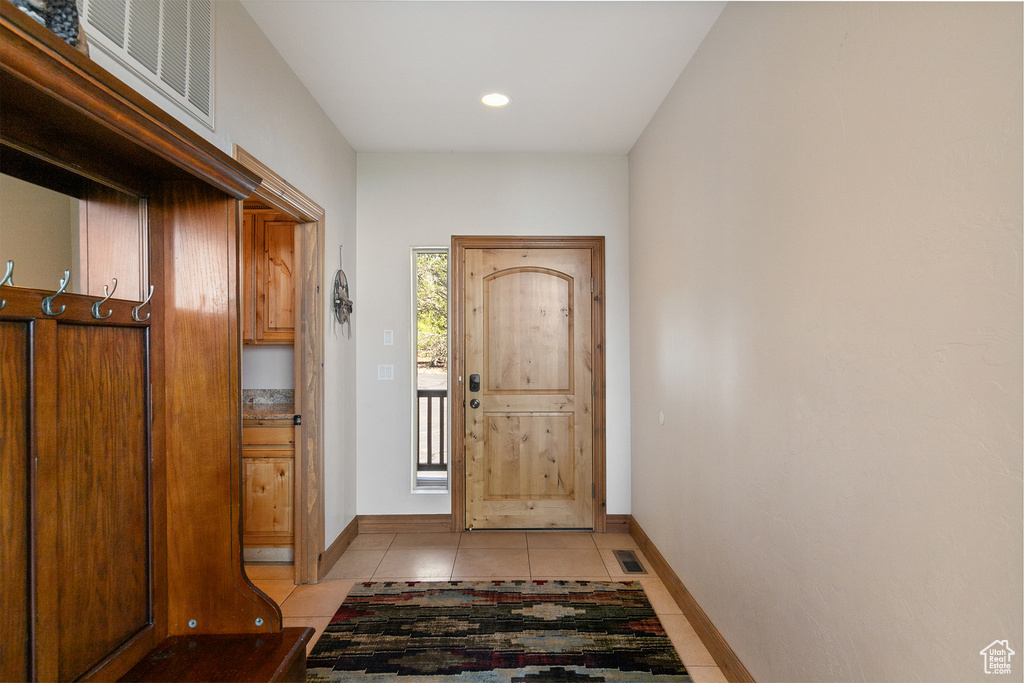 Entrance foyer with light tile patterned flooring and recessed lighting