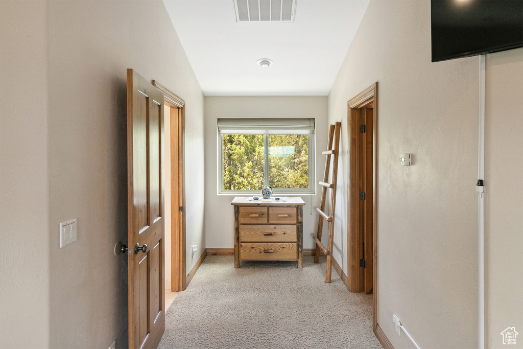 Corridor featuring light carpet and baseboards