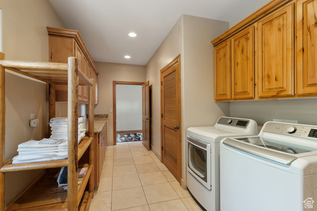Laundry room with washing machine and dryer, cabinet space, light tile patterned flooring, and recessed lighting