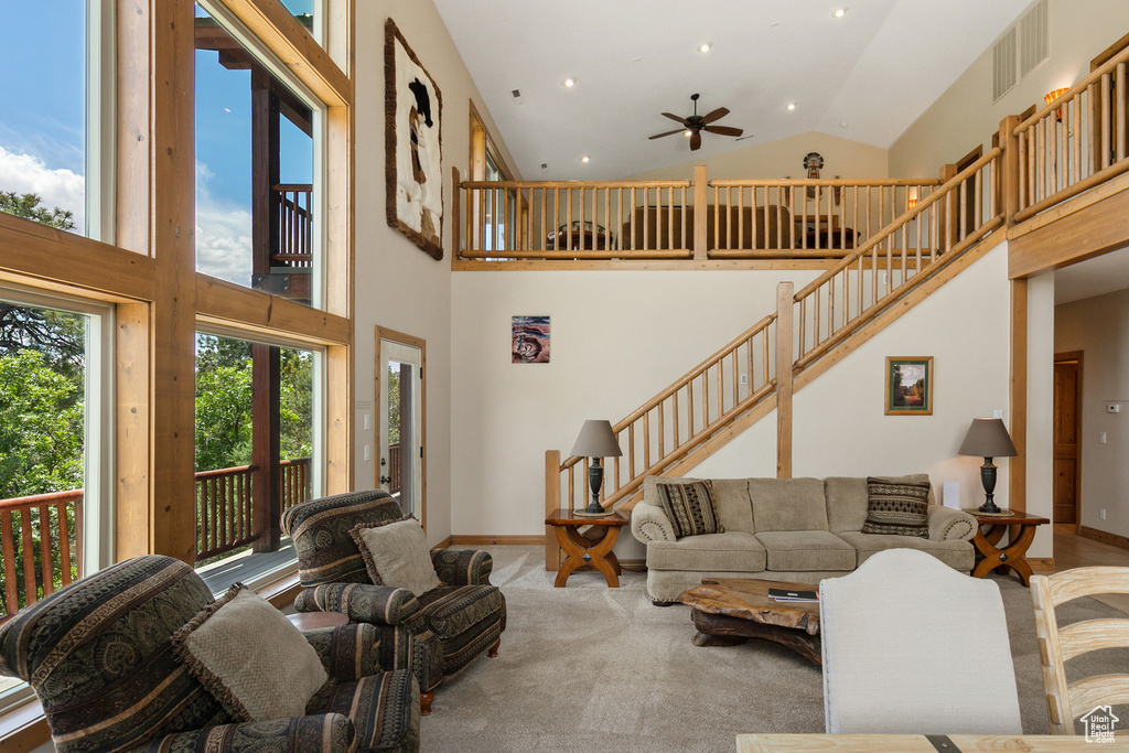 Living room featuring high vaulted ceiling, ceiling fan, stairway, carpet flooring, and recessed lighting