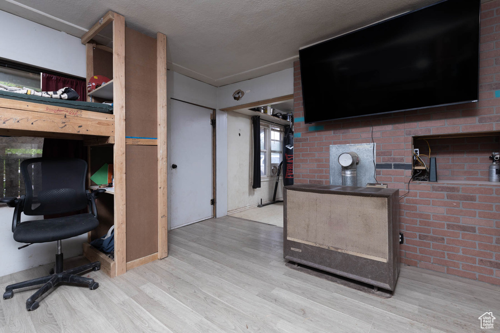 Bedroom with wood finished floors, an office area, and a textured ceiling