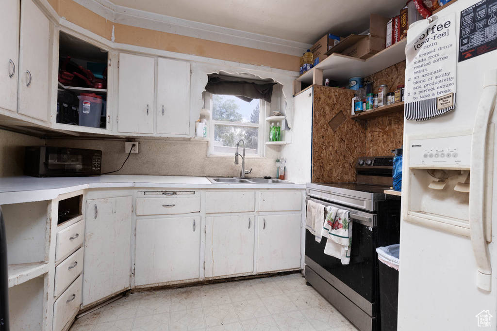 Kitchen with stainless steel range with electric cooktop, open shelves, white fridge with ice dispenser, light flooring, and light countertops