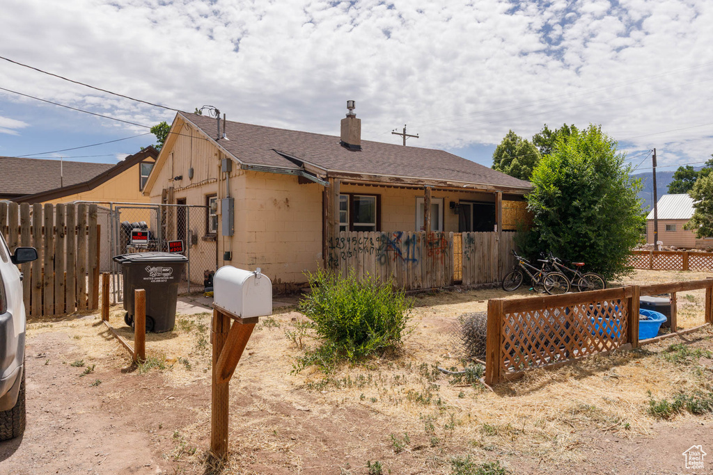 Rear view of property featuring a chimney, concrete block siding, and roof with shingles