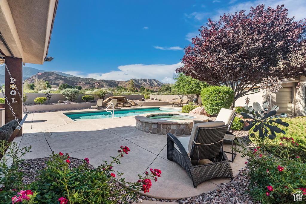 View of pool featuring a mountain view, an in-ground hot tub, a patio, and a fenced backyard
