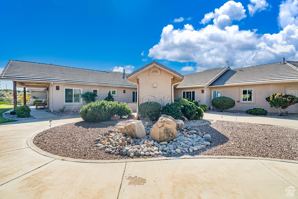 View of front of house with stucco siding, a tile roof, and driveway