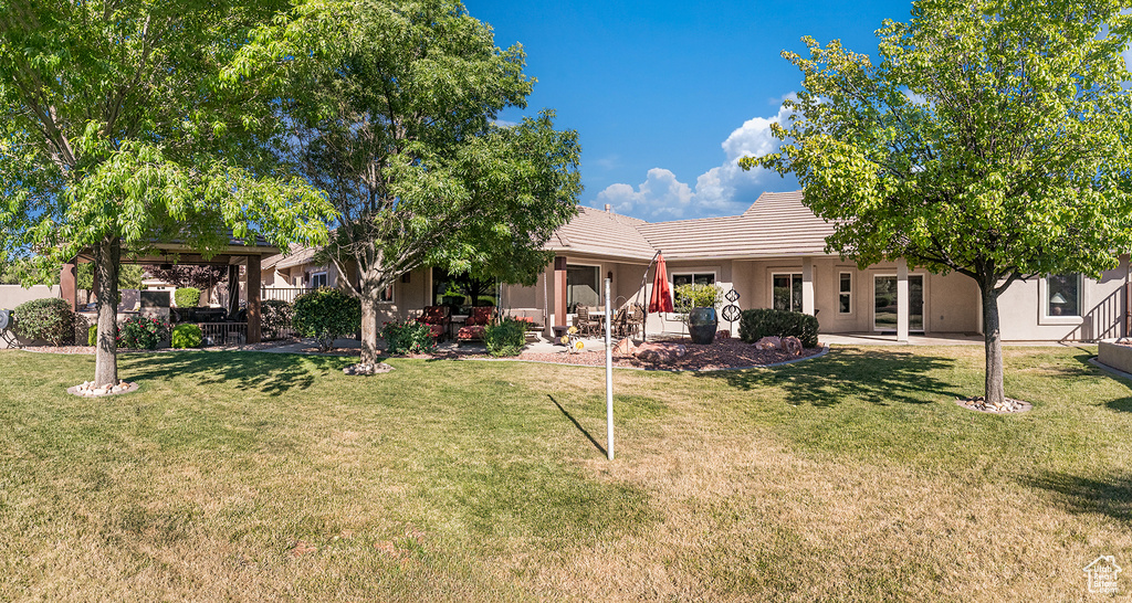 Back of property with a tile roof, a yard, a patio, and stucco siding