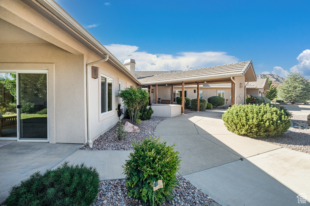 View of home's exterior featuring stucco siding, a chimney, and a patio area