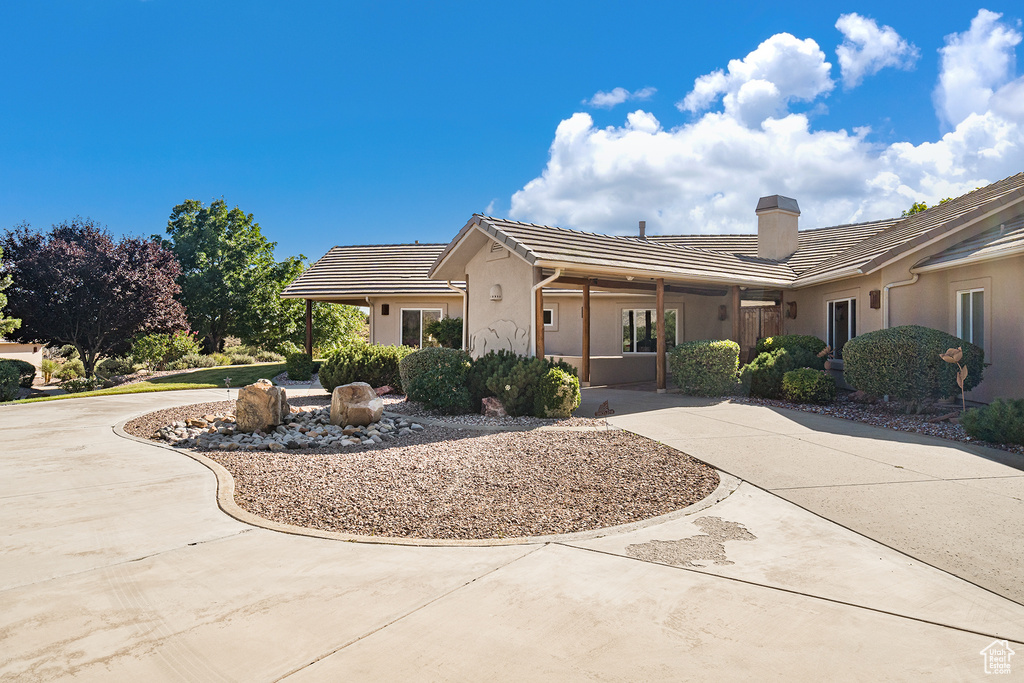 Single story home featuring driveway, a chimney, a tile roof, stucco siding, and an attached carport