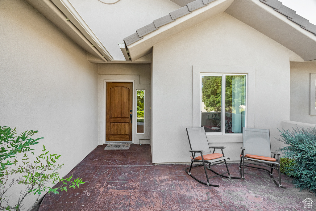Doorway to property featuring stucco siding and a patio