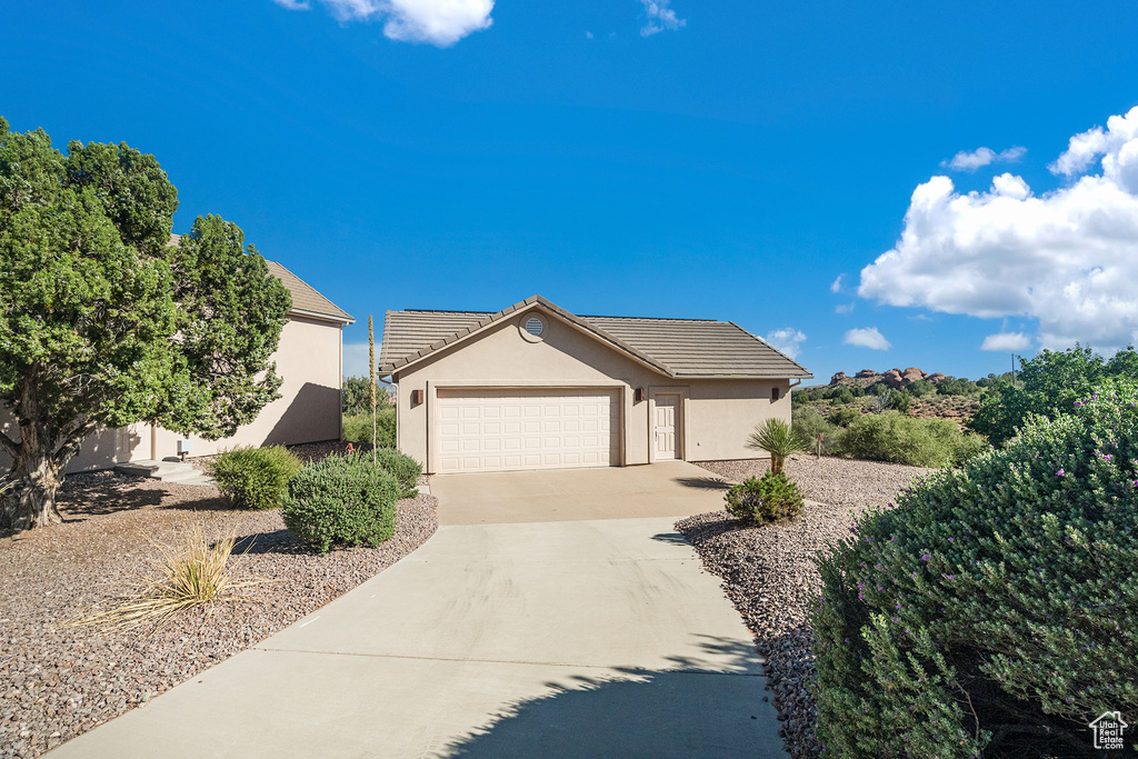 View of front of property featuring driveway, stucco siding, a garage, and a tile roof