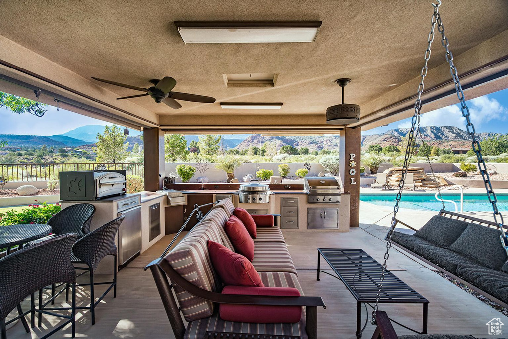 View of patio with area for grilling, outdoor lounge area, a mountain view, and ceiling fan