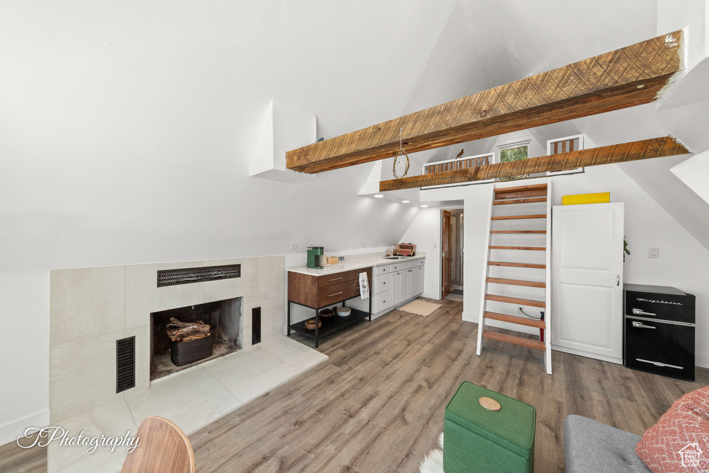 Living room with light wood-style flooring, a fireplace, and high vaulted ceiling