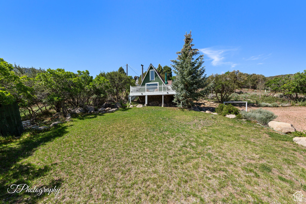 View of grassy yard featuring a wooden deck